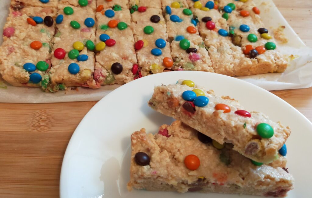 2 peices of M&M slice on awhite side plate with M&M slice in the background