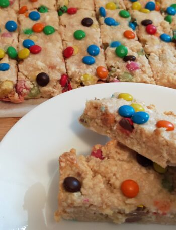 2 peices of M&M slice on awhite side plate with M&M slice in the background
