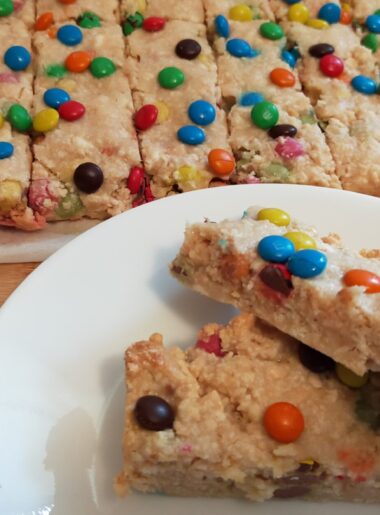 2 peices of M&M slice on awhite side plate with M&M slice in the background