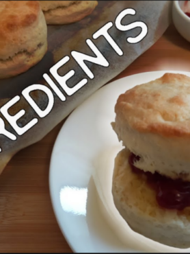 Scone on a side plate with butter and jam, in the background has the word 2 ingredients behind that some scones to the right some tubs with jam and butter.