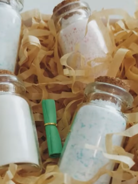 Little bottles of sherbet in a box sitting on brown shredded paper.