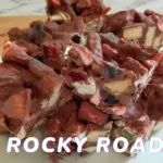 Pieces of homemade Rocky Road on a white board with chocolate, lollies and marshmallows visible