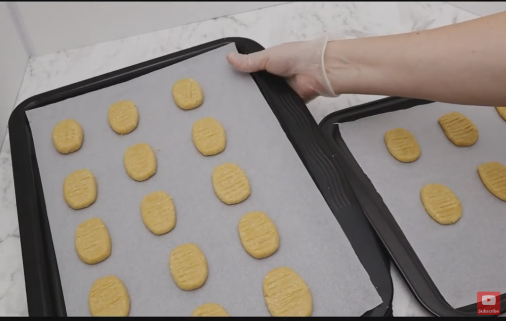 Baking trays with baking paper and non cooked monte carlo biscuits.