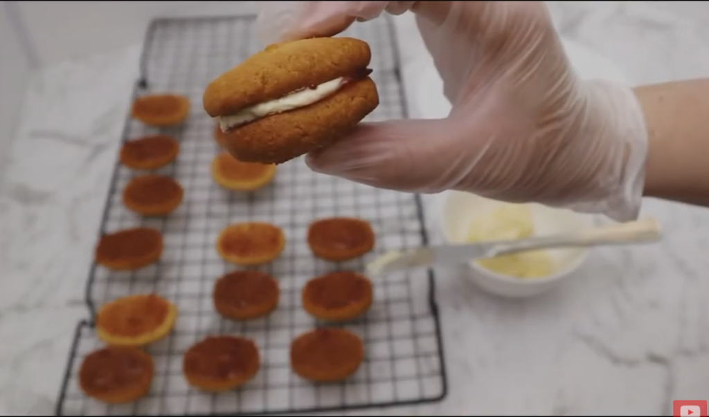 Baking cooling rack with monte carlo halves with jam ready to be sandwiched together. Forfront of the picture has a Monte Carlo Sandwich.