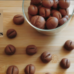 Coffee Bean Shaped Cookies in a jar with some scattered around the bench
