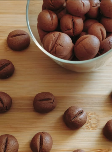 Coffee Bean Shaped Cookies in a jar with some scattered around the bench