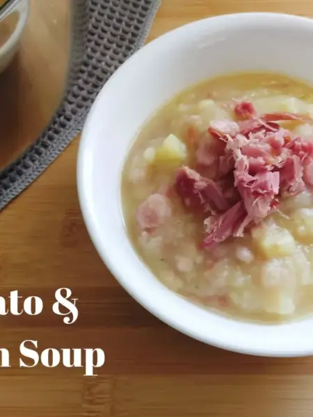 Bowl of Potato and Bacon soup with a soup spoon to the right and a pot of Potato and Bacon soup on the back left side.