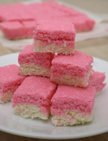 Pink and white coconut ice squares stacked on a plate