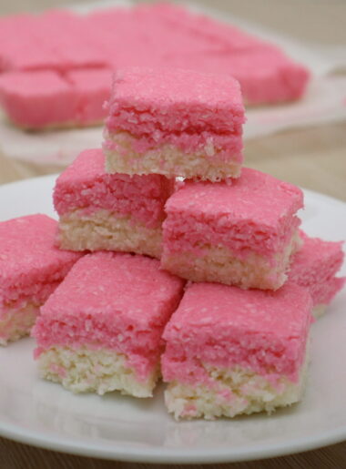 Pink and white coconut ice squares stacked on a plate