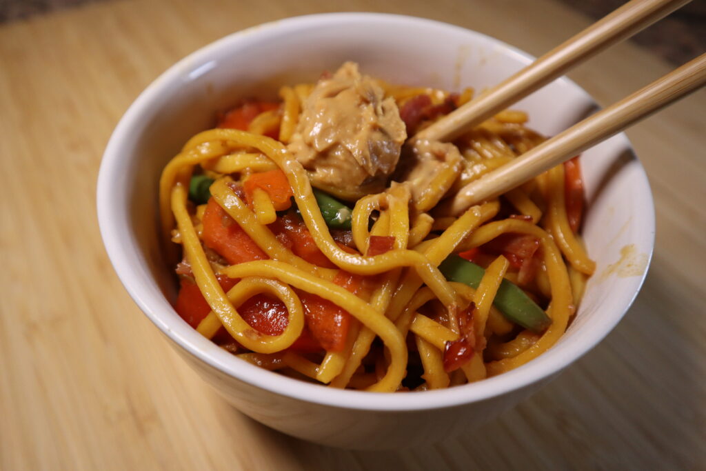 Hokkien Noodles in a asian bowl with chopsticks and a dolop of peanut butter.