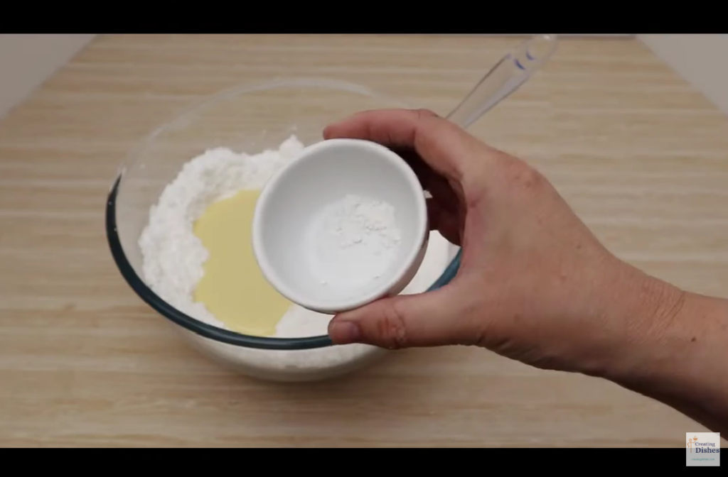 Placing cream of tartar in the coconut slice ingredients.