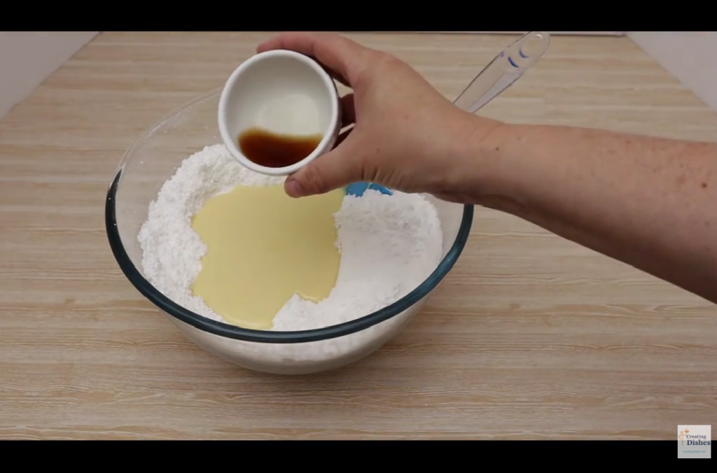 Coconut Ice: adding vanilla essence to the other ingredients.