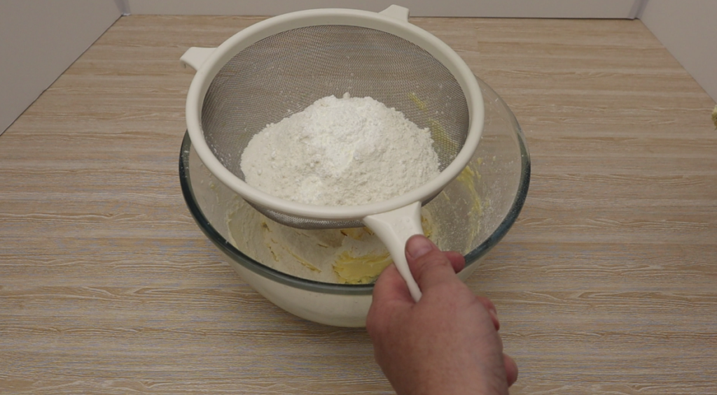 Sifting flour and corn flour into a bowl.