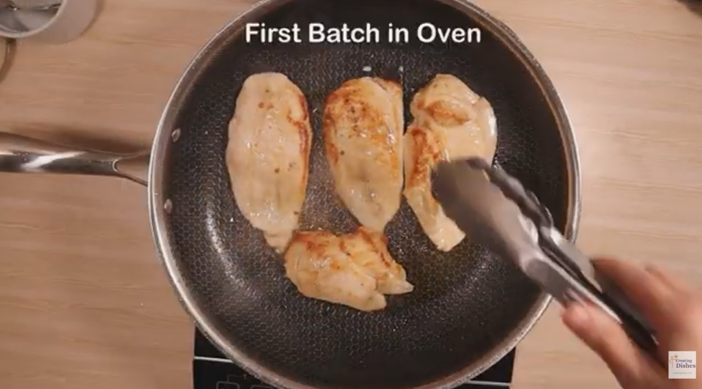 Chicken breast halves are being cooked in a pan 