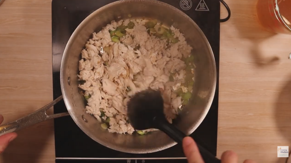 Saucepan with spring onion, garlic, ginger and shredded chicken