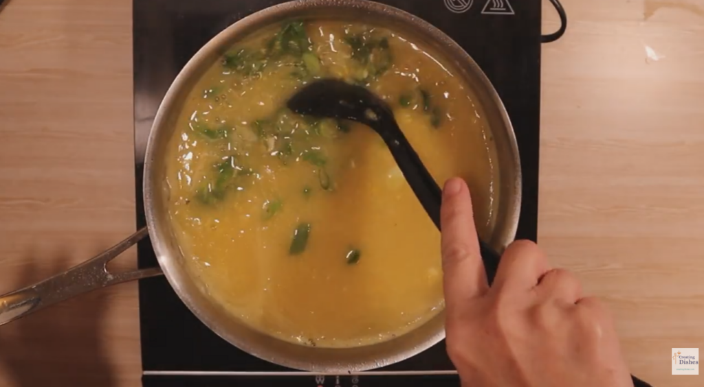 Adding Green spring onion to the chicken and sweet corn soup.