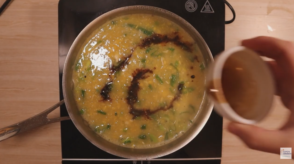 Adding soy sauce to chicken and sweet corn soup