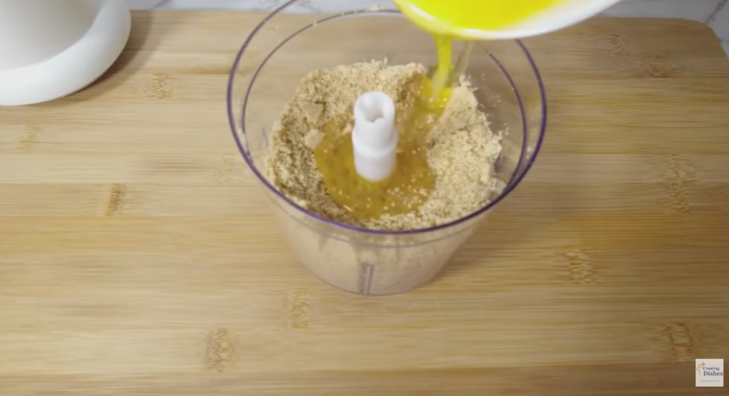 Adding melted butter to the crushed biscuits.