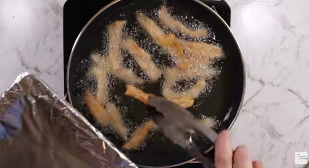 Pork strips frying in oil.